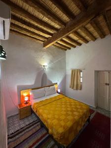 a bedroom with a bed with a yellow bedspread at Riad Dar Zaouia in Zagora