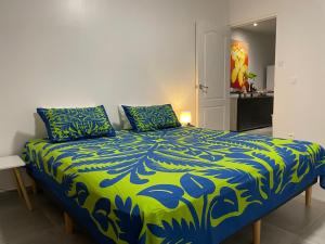 a bed with a blue and green comforter in a room at HeiHana House in Irioa