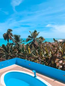 a pool with palm trees and the ocean in the background at Refúgio Lumare in Maragogi