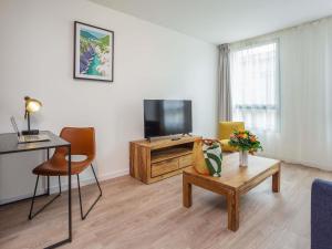 a living room with a tv and a table at Aparthotel Adagio Montpellier Centre Comedie in Montpellier