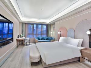 une chambre avec un grand lit blanc et un salon dans l'établissement Mercure Hangzhou Xixi Zijingang, à Hangzhou
