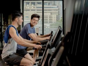 two men riding on a treadmill in a gym at Grand Mercure Bangkok Atrium in Bangkok