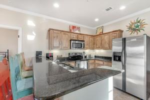 a kitchen with wooden cabinets and a stainless steel refrigerator at The Village at Gruene - Unit 201 in Gruene