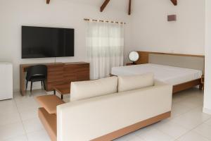 a bedroom with a bed and a couch and a tv at Hotel Albatros Wallis 