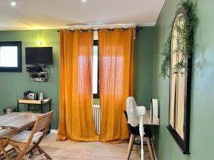 a dining room with orange curtains and a table at Studio centre Ville Lorient 3 4pers tout équipé in Lorient