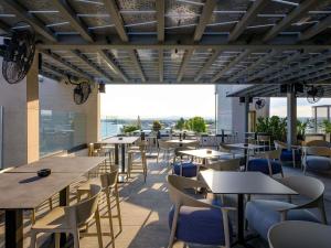 un restaurant avec des tables et des chaises et une grande fenêtre dans l'établissement Mercure Larnaca Beach Resort, à Larnaka