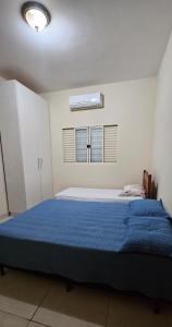 a bedroom with a large bed with a blue blanket at Casa Aconchegante in Cuiabá