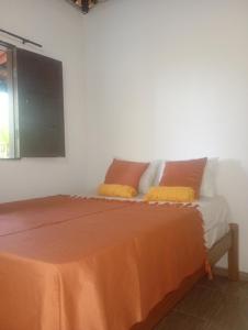 a bedroom with a bed with an orange sheet on it at Quarto Pé na Areia in Ilhéus