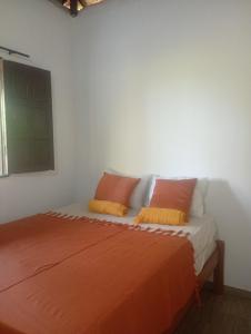 a bed with orange sheets and pillows in a room at Quarto Pé na Areia in Ilhéus