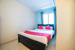 une chambre avec un lit avec des oreillers rouges et une fenêtre dans l'établissement Hotel Blue House, à Hyderabad