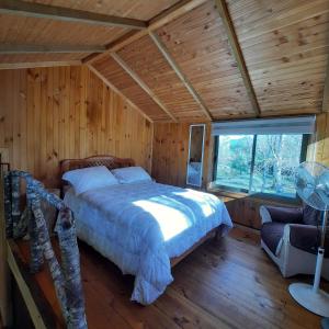 a bedroom with a bed and a window in a cabin at Domos Conguillío - Cabaña en el bosque in Melipeuco