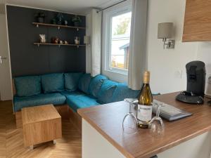 a living room with a blue couch and a bottle of wine at 6-Pers chalet Lauwersoog in Lauwersoog +20 photos