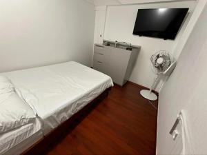 um pequeno quarto com uma cama e uma ventoinha em Aparta Suite Torre De Prado 305 em Medellín