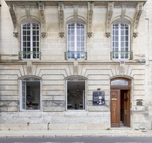 a building with four windows and a wooden door at Les appartements de l'Orangerie in Jarnac