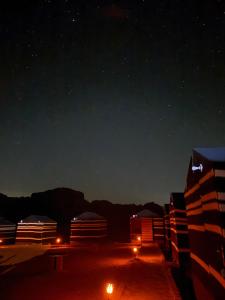 a starry night with the milky way and buildings at Wadi rum galaxy camp in Wadi Rum