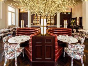 a restaurant with two tables and chairs and a vase at The Municipal Hotel Liverpool - MGallery in Liverpool