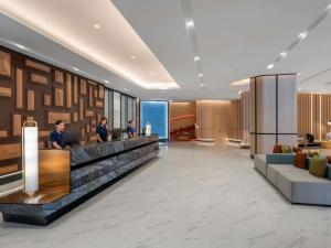 Un vestíbulo de un hotel con dos personas de pie en un mostrador. en Novotel Rayong Star Convention Centre, en Rayong