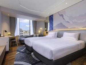 a hotel room with two beds and a desk at Novotel Rayong Star Convention Centre in Rayong