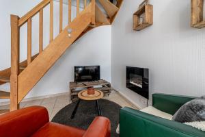 a living room with a couch and a tv and stairs at Duplex L'atelier Cosy en plein centre de Mordelles in Mordelles