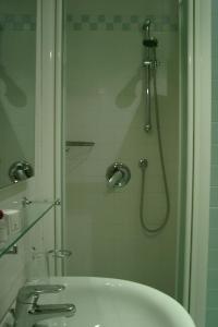 a shower with a glass door next to a sink at Hotel Gala in Pesaro