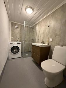 a bathroom with a toilet and a washing machine at Ny leilighet i Stjørdal in Stjoerdal