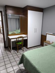a bedroom with a desk and a bed and a chair at Flat praia Vila Velha ES in Vila Velha +10 photos