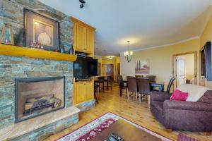 a living room with a stone fireplace and a couch at Aspens 4607 in Big White