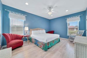 a bedroom with blue walls and a bed and a red chair at Sea La Vie in Gulf Shores
