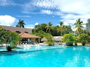 a large swimming pool with white chairs and palm trees at Coronado Luxury Club and Suites,Oasis in El Quije