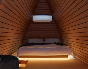 a bed in a wooden room with a window at Cabanas Farol in Pântano Grande