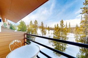 a balcony with a chair and snow covered trees at Timber Ridge 203 in Silverthorne