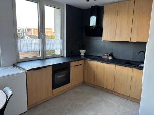 a kitchen with wooden cabinets and a dishwasher at Apartament w Centrum Miasta in Brodnica