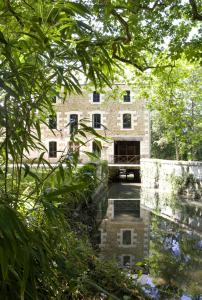 un vieux bâtiment en pierre avec un reflet dans l'eau dans l'établissement Authentique moulin à eau du ⅫⅠe siècle, à La Vernelle