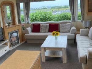 a living room with a couch and a table and a fireplace at Brynowen Holiday Park - Holiday Accommodation 19041 in Borth