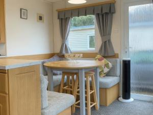 a small kitchen with a table and stools in a caravan at Brynowen Holiday Park - Holiday Accommodation 19041 in Borth