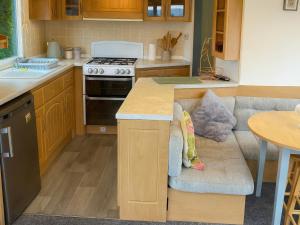 a kitchen with a stove and a couch in it at Brynowen Holiday Park - Holiday Accommodation 19041 in Borth +1 photo