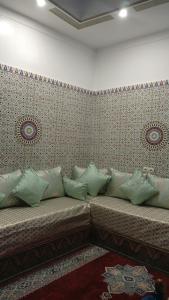 a couch with green pillows against a wall at Chez Faiza in Rabat