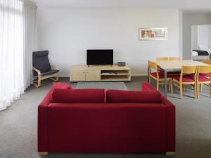 a living room with a red couch and a table at Mantra Castle Hill Sydney, an Accor Hotel in Castle Hill
