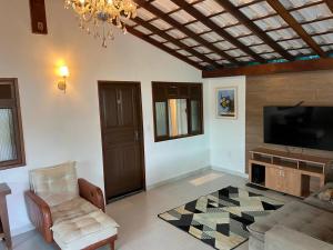 a living room with a couch and a flat screen tv at Chalé com Ar Condicionado Praia Seca in Araruama