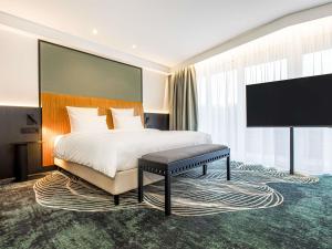 a hotel room with a bed and a flat screen tv at Mercure Palanga Vanagupe Resort & SPA in Palanga