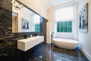 a bathroom with a tub and a sink and a window at The Victorian Residence in Moffat