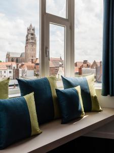 a window seat with pillows in front of a window at Hotel Portinari in Bruges