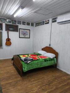 a bedroom with a bed in a room with a guitar at Recanto do Zeca in Bento Gonçalves