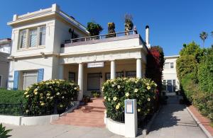 een wit huis met bloemen ervoor bij Chapala Gardens Historic West Beach 1BR - Unit 2 in Santa Barbara
