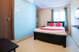 une chambre avec un lit avec des oreillers rouges et une fenêtre dans l'établissement Hotel Blue House, à Hyderabad
