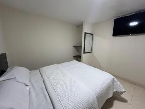a bedroom with a white bed and a flat screen tv at Hotel Monaco in Ipiales +4 photos