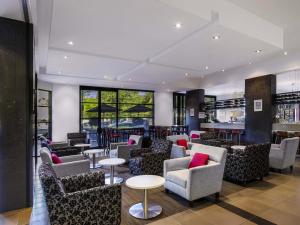 Un vestíbulo con sillas y mesas y un bar. en Mantra Hindmarsh Square, en Adelaida
