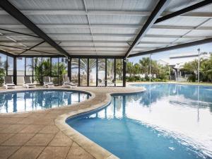 a large swimming pool with chairs and a building at Mantra Geraldton in Geraldton