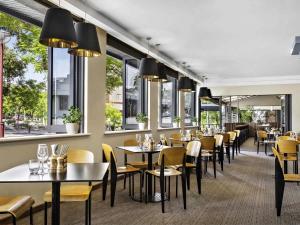 a restaurant with tables and chairs and windows at Mantra on Hay Perth in Perth