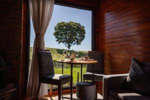 a dining room with a table and chairs and a window at Capanna del Vale - Refúgio & Degustação no Vale dos Vinhedos in Bento Gonçalves